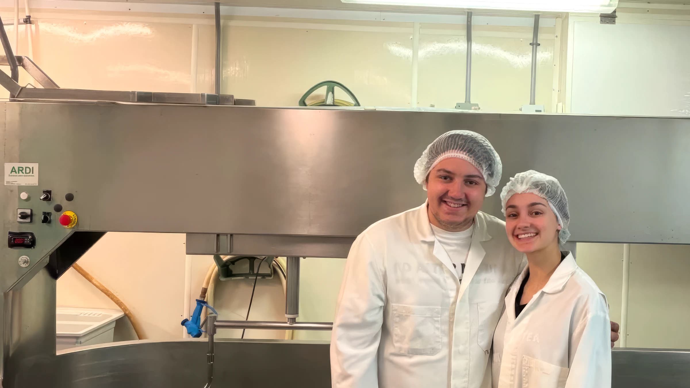 Les propriétaires de la fromagerie, en sarrau, devant le bassin de fabrication